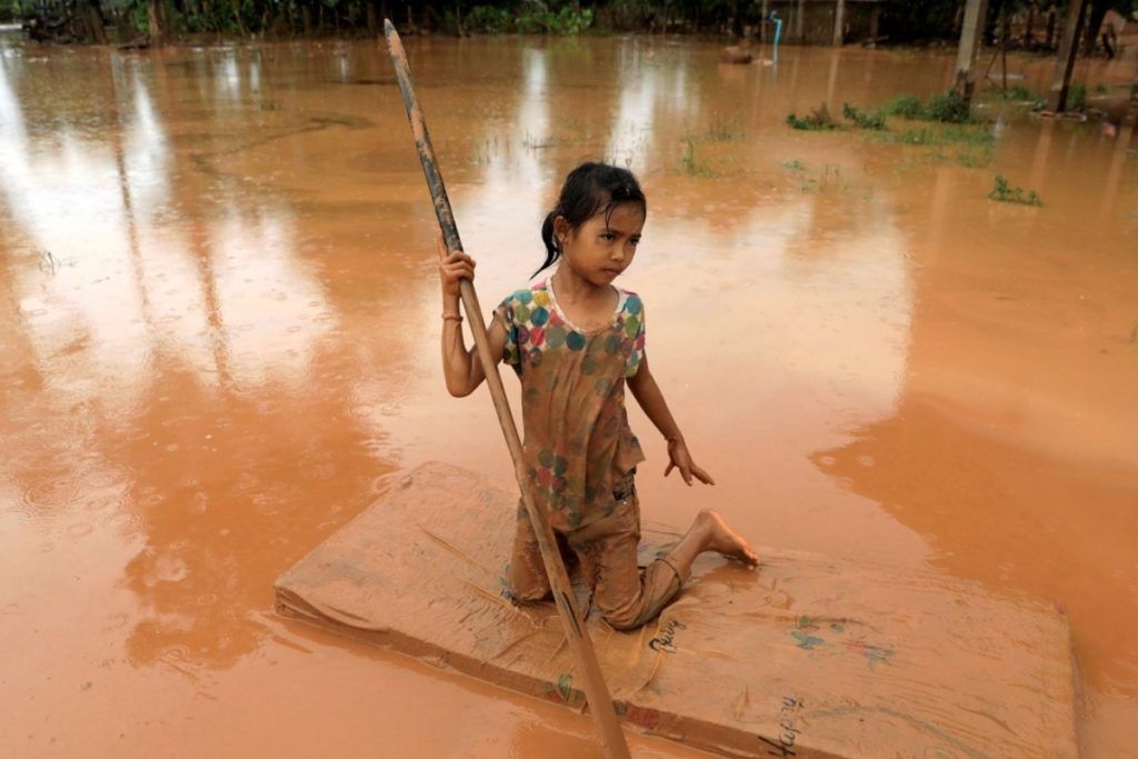 Một bé gái dùng nệm làm xuồng di chuyển trong đợt lũ lụt vào năm 2018 tại tỉnh Attapeu, Lào. Ảnh: Reuters