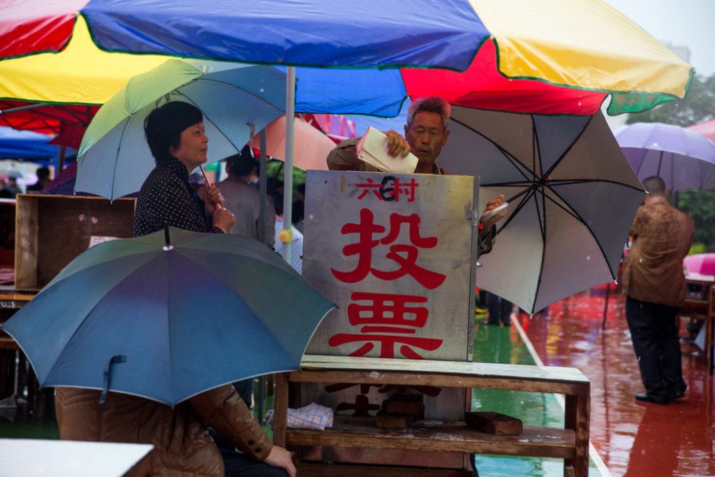 Dân thôn Ô Khảm, tỉnh Quảng Đông đội mưa bỏ phiếu trong cuộc bầu cử thôn vào tháng 4/2014. Ảnh: Sim Chi Yin/ New York Times.